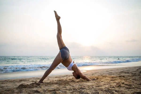 Donna incinta dall'aspetto naturale che pratica yoga in riva al mare a — Foto Stock