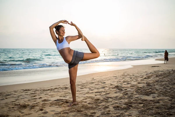 Mujer embarazada de aspecto natural practicando yoga en la orilla del mar a — Foto de Stock