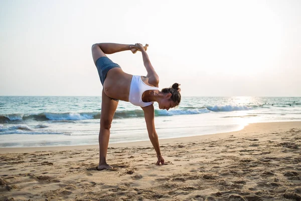 Mujer embarazada de aspecto natural practicando yoga en la orilla del mar a — Foto de Stock