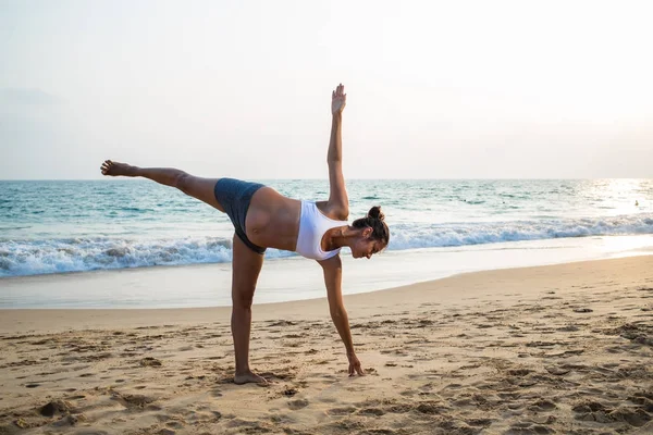 Mujer embarazada de aspecto natural practicando yoga en la orilla del mar a — Foto de Stock