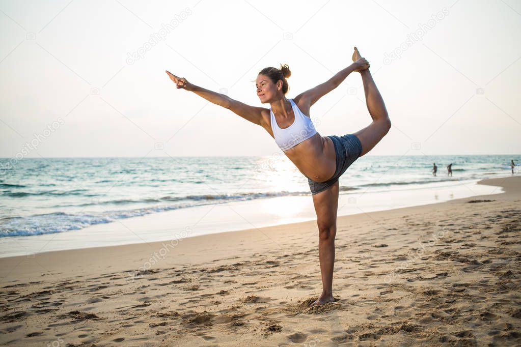 Natural looking pregnant woman practicing yoga at the seashore a
