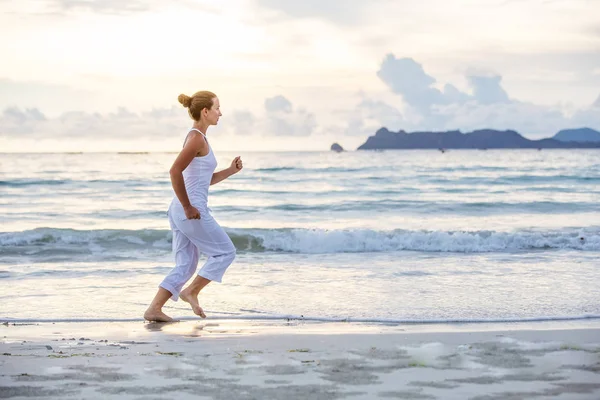 Kaukasische vrouw joggen op kust — Stockfoto