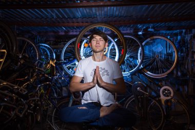 Genç adam birçok bisiklet ile garajda yoga uygulamak