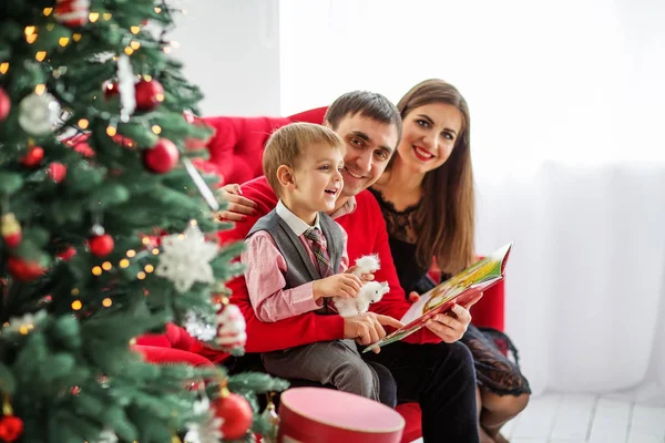 幸福的家庭在圣诞树旁看书 — 图库照片