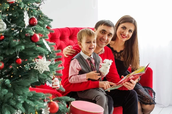 幸福的家庭在圣诞树旁看书 — 图库照片