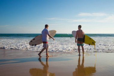 İki adam sahilde bir surfboard ile