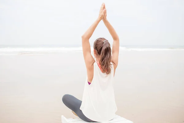 Mujer practica yoga en la orilla del mar en día nublado — Foto de Stock