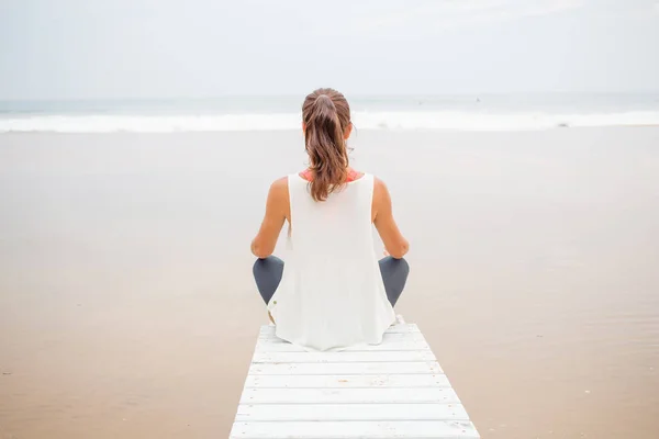 Kvinna praxis yoga på havsstranden på mulen dag — Stockfoto