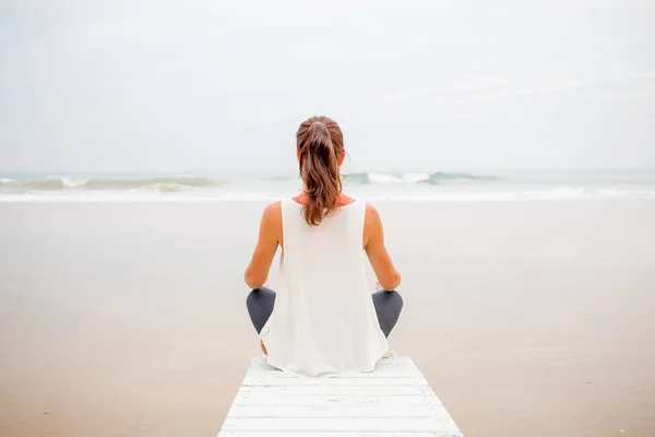 Kvinna praxis yoga på havsstranden på mulen dag — Stockfoto