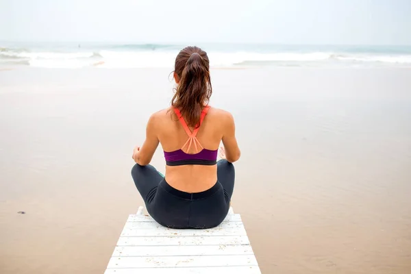 Kvinna praxis yoga på havsstranden på mulen dag — Stockfoto