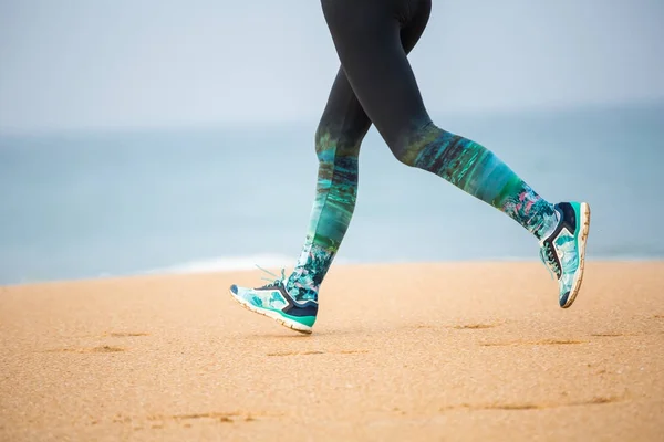 Kvinnan jogging längs havsstranden på en mulen dag — Stockfoto