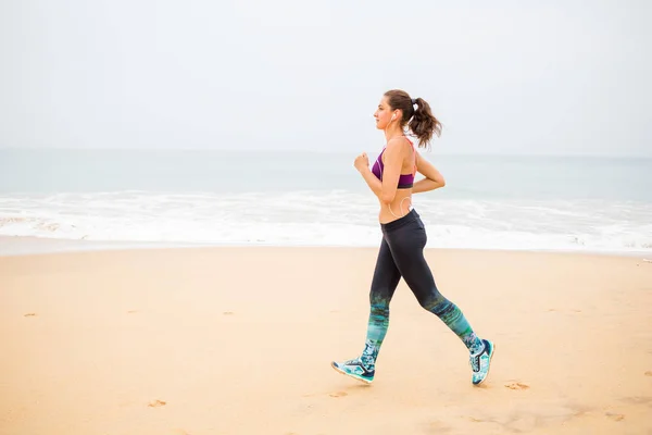 Kvinnan jogging längs havsstranden på en mulen dag — Stockfoto