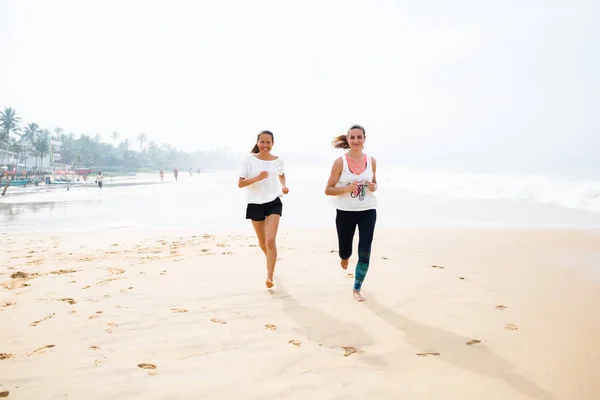 Två kvinnor jogging havsstranden på en mulen dag — Stockfoto
