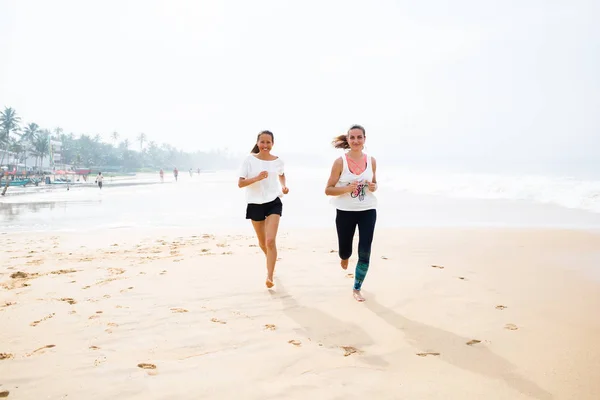 Twee vrouwen is de kust joggen op een bewolkte dag — Stockfoto