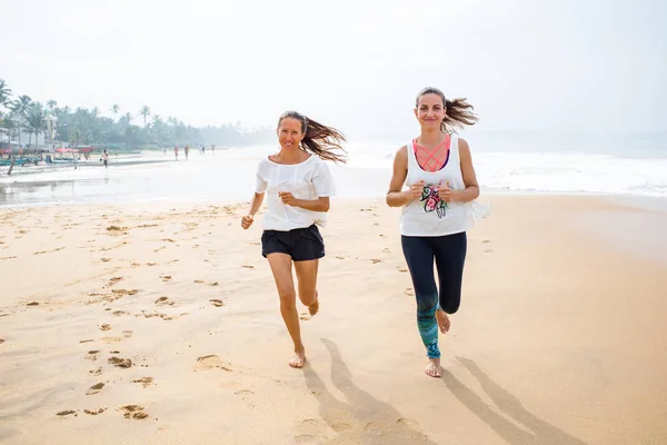 Två kvinnor jogging havsstranden på en mulen dag — Stockfoto