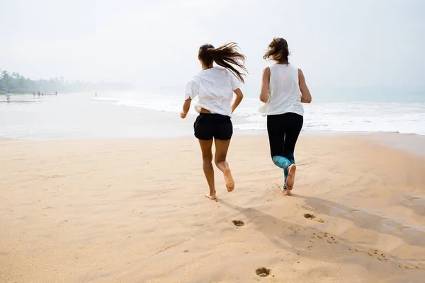 Två kvinnor jogging havsstranden på en mulen dag — Stockfoto