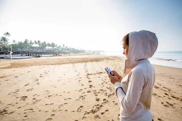 Mujer joven está escuchando la música en el teléfono antes de trotar — Foto de Stock