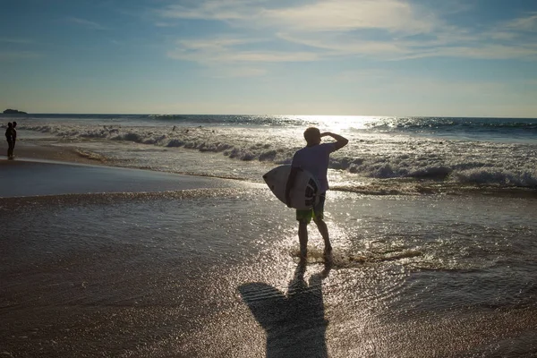 Un hombre con una tabla de surf en la playa — Foto de Stock