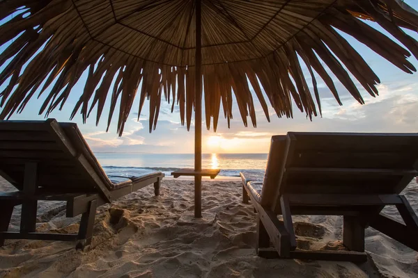 Espreguiçadeiras com guarda-chuva na praia, nascer do sol — Fotografia de Stock