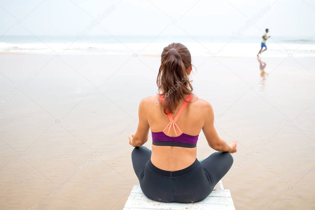 Woman practices yoga at the seashore on overcast day