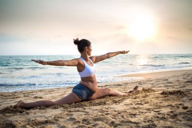 Doğal görünümlü hamile kadın seashore Yoga pratik bir