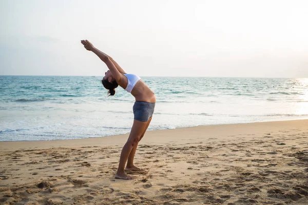 Natürlich aussehende schwangere Frau praktiziert Yoga an der Küste ein — Stockfoto