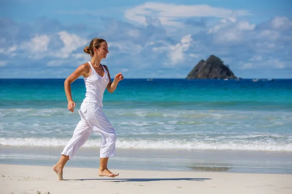 Kaukasische vrouw joggen op kust — Stockfoto