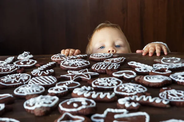 Menino pequeno tenta pegar gengibre de Natal caseiro tradicional e — Fotografia de Stock