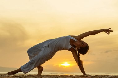 Kadın uygulamaları yoga gün batımında indone içinde seashore Bali
