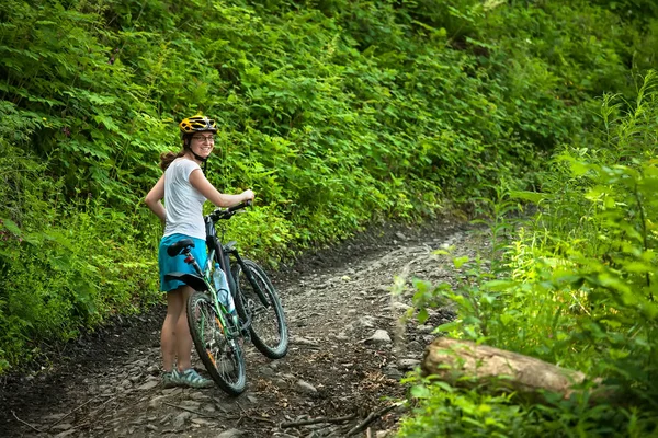 Biker popycha rower w zielonym lesie — Zdjęcie stockowe
