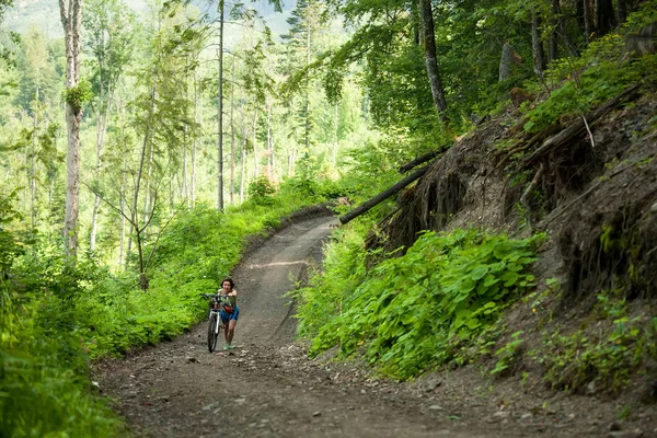 Motociclista empuja bicicleta en el bosque verde —  Fotos de Stock