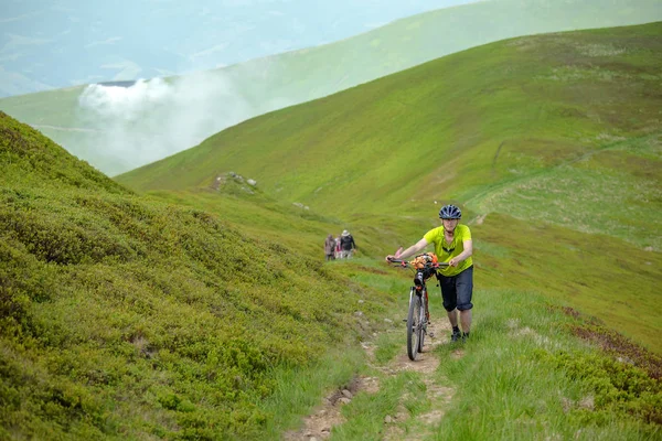 Motociclista empurra bicicleta nas montanhas — Fotografia de Stock