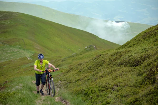 Motociclista empuja bicicleta en las montañas —  Fotos de Stock