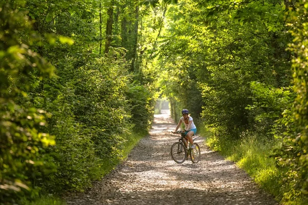 Kadın güzel yeşil ormanın içinde bisiklet ile gidiyor