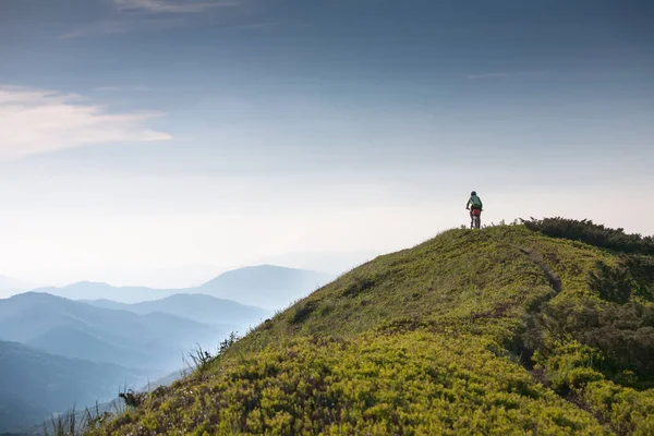 Woman rides bicycle up in the mountains — Stock Photo, Image