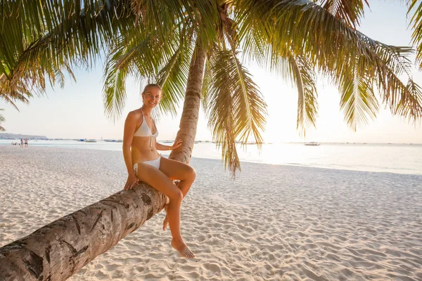 Mujer descansa en la palmera cerca del océano al atardecer — Foto de Stock