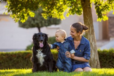 Bir anne ile bebek evlat ve yeşil mahallede siyah köpek