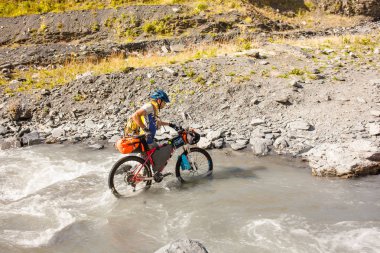 Dağ bisikletçinin Tusheti dağlık nehir geçiyor