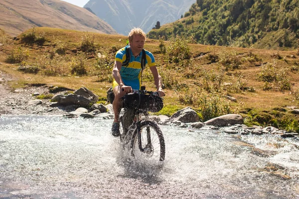 Ciclista de montaña está cruzando el río en las tierras altas de Tusheti —  Fotos de Stock