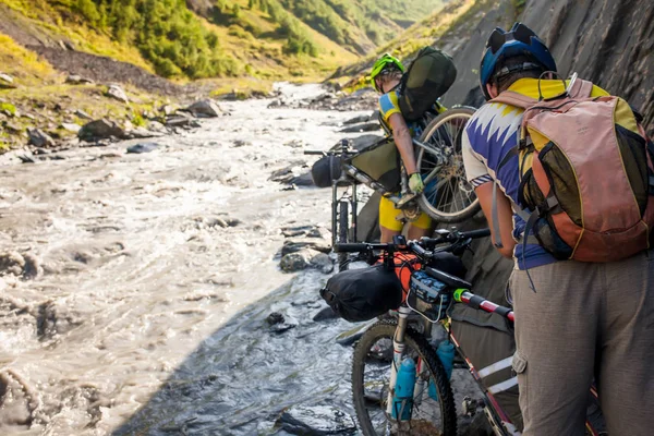 Mountain biker jest na rzece w górach Tuszetii — Zdjęcie stockowe