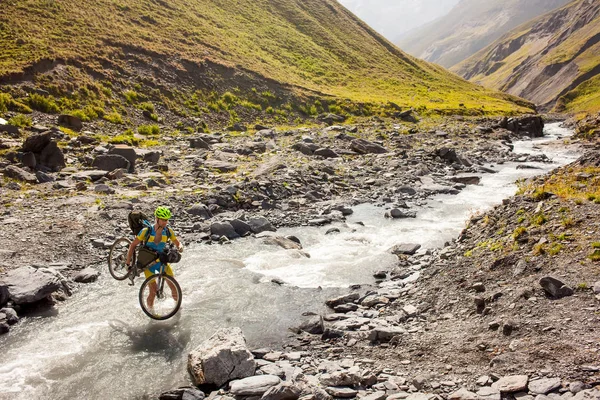 Ciclista de montaña está cruzando el río en las tierras altas de Tusheti —  Fotos de Stock