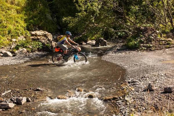 Ciclista de montaña está cruzando el río en las tierras altas de Tusheti —  Fotos de Stock