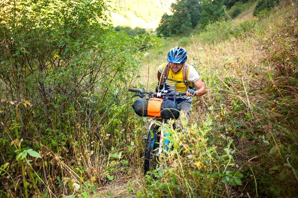Biker popycha jego rower w wysokich górach Kaukazu — Zdjęcie stockowe