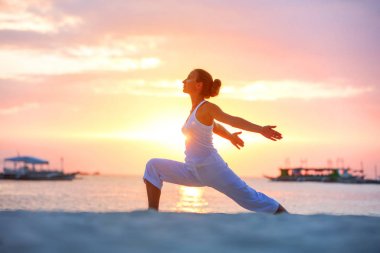 Bir kadın Boracay Adası'nda gün batımında yoga egzersizleri yapıyor,