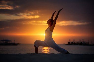 Bir kadın Boracay Adası'nda gün batımında yoga egzersizleri yapıyor,