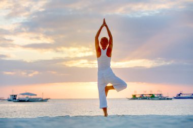 Bir kadın Boracay Adası'nda gün batımında yoga egzersizleri yapıyor,