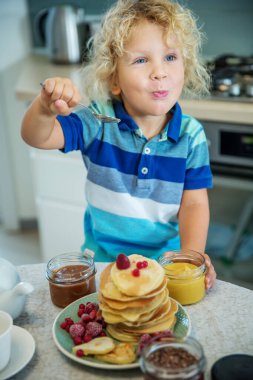 Küçük kıvırcık çocuk tatlı krep yiyor