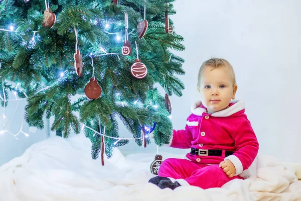 Malý chlapec v santa oblek hraje v blízkosti novoroční strom — Stock fotografie