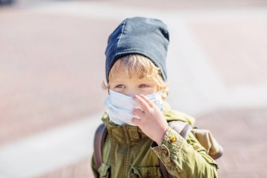 Dışarıdaki koruma maskeli küçük çocuk.