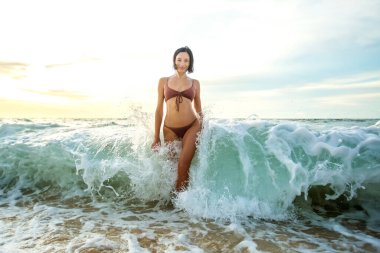 Gün batımında okyanusun kenarında güzel bir kadın